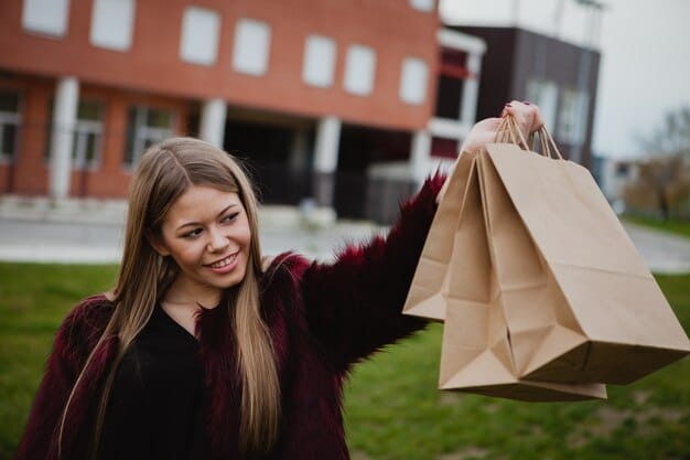A young, stylish student happily holding a Shein package outside their college dorm. They are wearing a fashionable outfit from Shein, showcasing the brand's trendy clothing. The background includes a bustling college campus scene with backpacks, bicycles, and fellow students walking by, highlighting the student's active lifestyle.