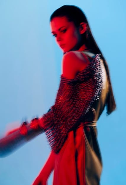 Close-up shot of a runway model showcasing a top with architectural statement sleeves made of sheer, layered fabric. The lighting highlights the intricate construction and texture of the sleeves.