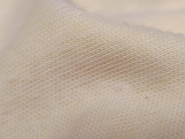 A close-up of a light beige linen fabric swatch. The texture is slightly wrinkled and shows the natural weave of the fibers. The fabric has a soft, matte appearance.