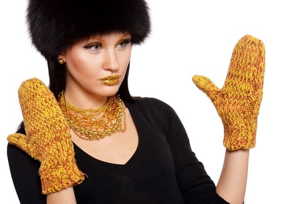 A close-up shot of a model wearing a chunky gold necklace and large, sparkly earrings at a winter holiday party, showcasing the oversized jewelry trend.