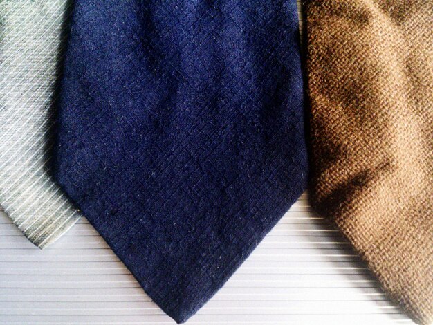A close-up shot of various power suit fabrics, showcasing textures like wool blends, corduroy, and velvet in autumnal colors (burgundy, forest green, mustard yellow). The image also features details like interesting button designs and stitching patterns.