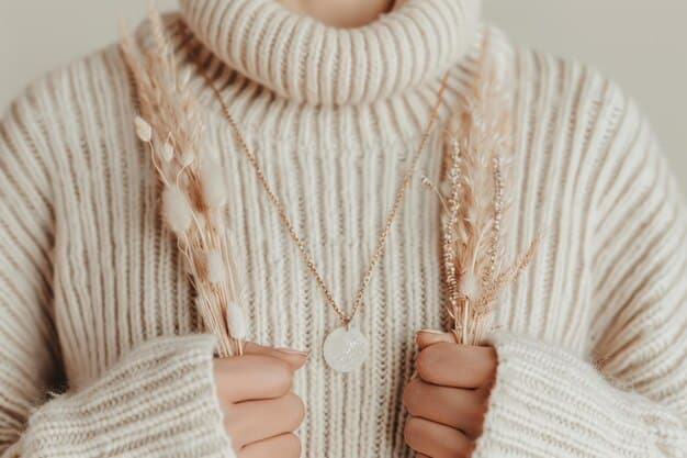 A close-up shot of a textured, wide-ribbed knit sweater in a neutral cream color, paired with a subtle gold chain necklace, illustrating comfort and elevated style.