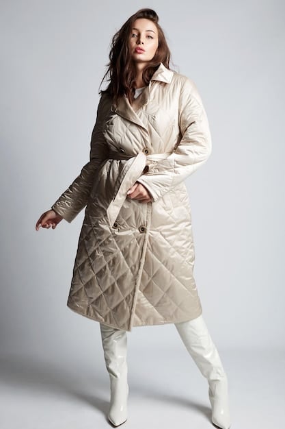 A model gracefully showcasing a stylish quilted jacket in a muted tone, paired with high-waisted wide-leg trousers, standing in an urban outdoor setting. The image highlights the jacket's texture and the trousers' flow, conveying a casual yet chic aesthetic suitable for January weather.