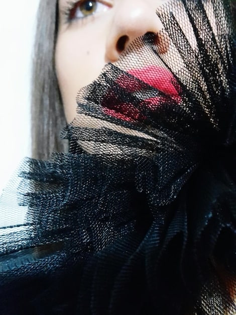 A detailed shot of a vibrant abstract art print on a silk scarf, tied loosely around the neck of a model wearing a simple black top, highlighting the scarf as a focal point.